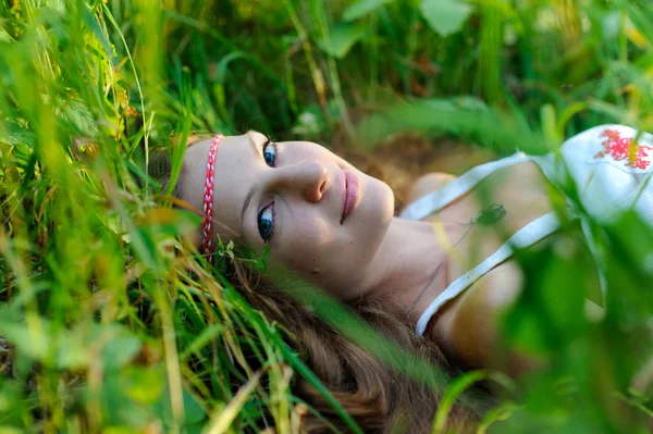 Jeune belle fille slave aux cheveux longs et vêtements ethniques slaves se trouve dans l'herbe dans une forêt d'été — Photo