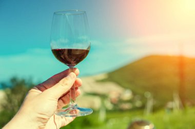 Güneşin bir dağ manzarası ile bir arka plan üzerinde kırmızı şarap bir bardak