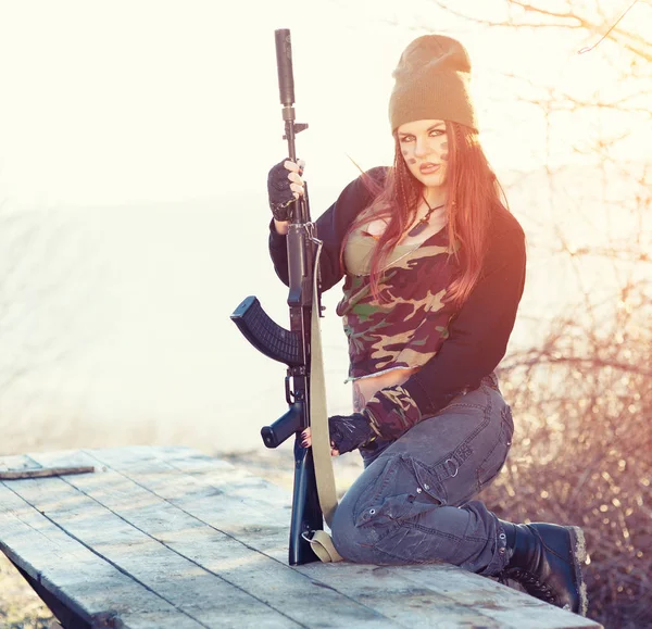 Mulher sexy com uma arma ao ar livre nos raios de um sol brilhante. Tom de cor vintage — Fotografia de Stock