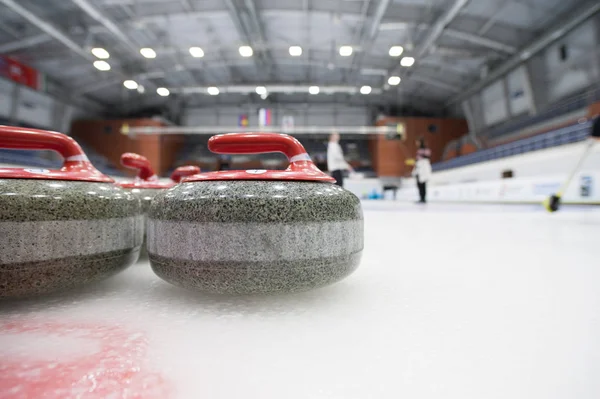 Uma concha para curling no gelo contra o fundo de jogar atletas — Fotografia de Stock