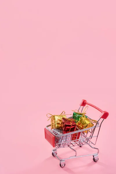 Annual sale, Christmas shopping season concept - mini red shop cart trolley full of gift box isolated on pale pink background, copy space, close up — Stock Photo, Image
