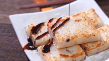 Lezzetli şalgam kekinin üzerine kara soya sosu dök restoranda geleneksel Çin turplu keki, kapat, uzayı kopyala.