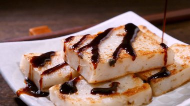 Lezzetli şalgam kekinin üzerine kara soya sosu dök restoranda geleneksel Çin turplu keki, kapat, uzayı kopyala.