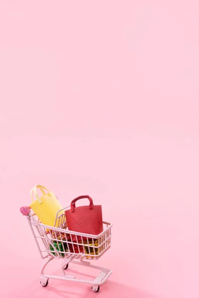 Annual sale shopping season concept - mini pink shop cart trolley full of paper bag gift isolated on pale pink background, blank copy space, close up — Stock Photo, Image