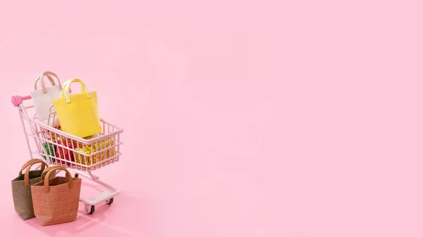 Concepto de temporada de compras de venta anual mini carro de la tienda rosa lleno de regalo bolsa de papel aislado sobre fondo rosa pálido, espacio de copia en blanco, primer plano —  Fotos de Stock