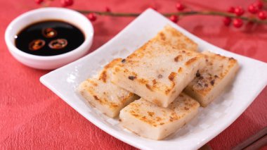 Çin 'in yeni yıl yemeği konsepti, enfes turp keki, kırmızı arka planda soya sosu olan yerel bir restoran mutfağı, kapat, uzayı kopyala.