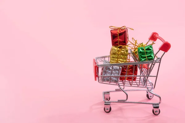 Annual sale, Christmas shopping season concept - mini red shop cart trolley full of gift box isolated on pale pink background, copy space, close up — Stock Photo, Image