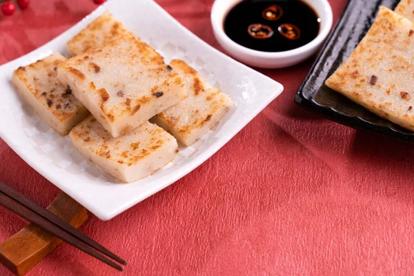 Concepto chino de comida de año nuevo lunar, Delicioso pastel de rábano nabo, cocina local en restaurante con salsa de soja sobre fondo rojo, primer plano, espacio para copiar — Foto de Stock
