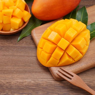 Taze mango, koyu ahşap masa arkasında yeşil yapraklı güzel doğranmış meyve. Tropik meyve tasarımı konsepti. Düz yatıyordu. Üst Manzara. Boşluğu kopyala