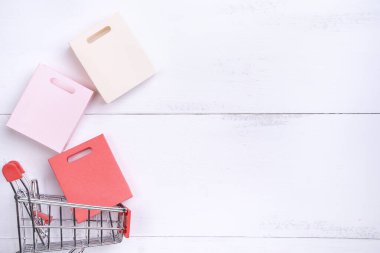 Soyut tasarım unsuru, yıllık satış, alışveriş sezonu konsepti, beyaz ahşap masa arka planında renkli kağıt çantalı mini araba, üst manzara, düz yatış