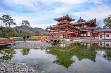 Uji, Japonya - Mart. 23, 2019: Japonya 'nın Kyoto, Uji şehrinde ilkbahar seferi görüntüsü ve göl suyu yansıması olan güzel bir Byodoin tapınağı..