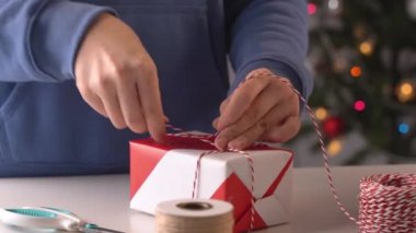 Mavili genç bir kadın çocuklara Noel hediyesi paketliyor. Güzel, kırmızı, beyaz ambalajlı, pırıl pırıl bir hayat tarzı var..