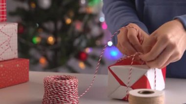 Mavili genç bir kadın çocuklara Noel hediyesi paketliyor. Güzel, kırmızı, beyaz ambalajlı, pırıl pırıl bir hayat tarzı var..