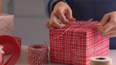 Mavili genç bir kadın çocuklara Noel hediyesi paketliyor. Güzel, kırmızı, beyaz ambalajlı, pırıl pırıl bir hayat tarzı var..