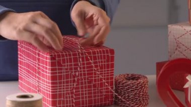 Mavili genç bir kadın çocuklara Noel hediyesi paketliyor. Güzel, kırmızı, beyaz ambalajlı, pırıl pırıl bir hayat tarzı var..