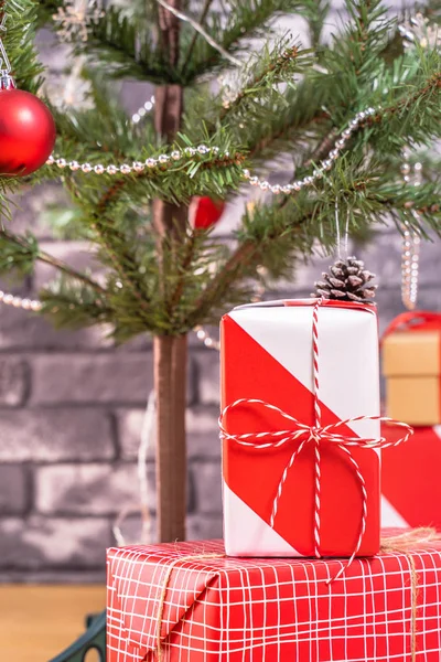 Dekorerad julgran med inslagna vackra röda och vita presenter hemma med svart tegelvägg, festlig design koncept, närbild. — Stockfoto