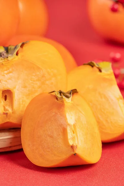 Čerstvé krásné plátky sladké persimmon kaki izolované na červeném pozadí stolu a bambusové síto, čínský lunární nový rok design koncept, zblízka. — Stock fotografie
