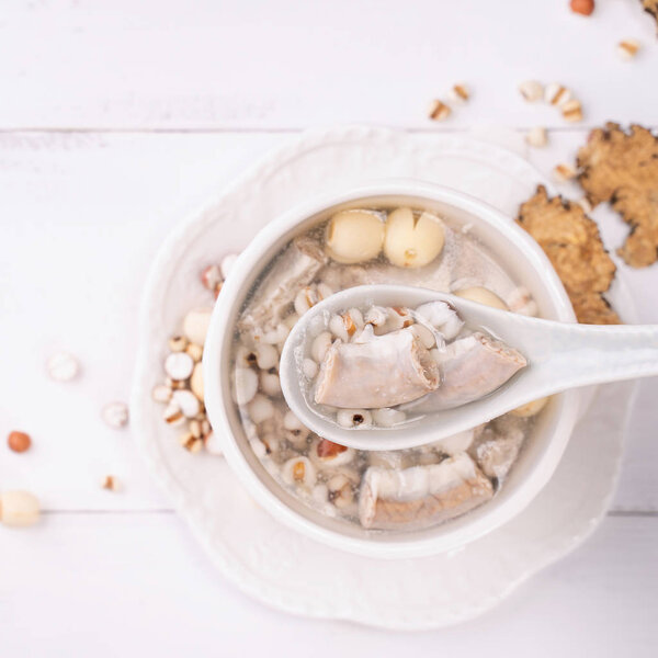 Tasty Four Tonics Herb Flavor Soup, Taiwanese traditional food with herbs, pork intestines on white wooden table, close up, flat lay, top view.