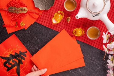 Çin 'in Ocak ayının yeni yılı tasarım konsepti - Kadın kucağında, kırmızı zarflar (ang pow, hong bao) para, üst görünüm, düz yatış, yukarıdaki. 