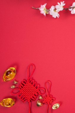 Çin 'in Yeni Yıl Tasarım Konsepti - Kırmızı arka planda izole edilmiş erik çiçeği olan güzel Çin düğümü, düz konum, üst manzara, genel görünüm.