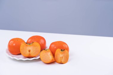 Gri mavi arka planı olan beyaz mutfak masasında izole edilmiş taze, dilimlenmiş tatlı hurma hurması, Çin 'in yeni yıl tasarım konsepti, yakın plan..