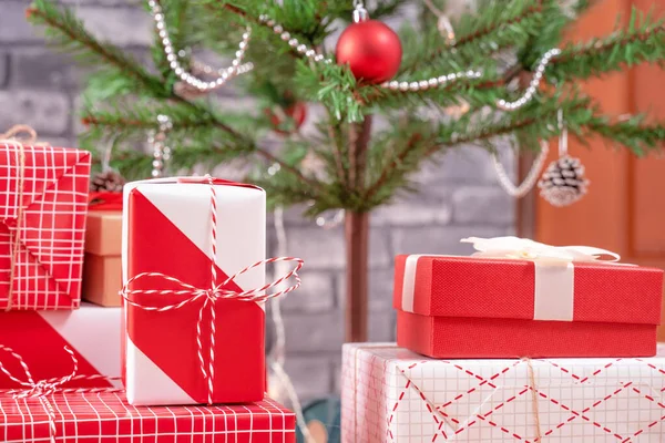 Árvore de Natal decorada com belos presentes vermelhos e brancos embrulhados em casa com parede de tijolo preto, conceito de design festivo, close-up. — Fotografia de Stock