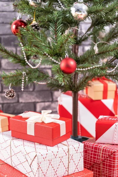 Árvore de Natal decorada com belos presentes vermelhos e brancos embrulhados em casa com parede de tijolo preto, conceito de design festivo, close-up. — Fotografia de Stock