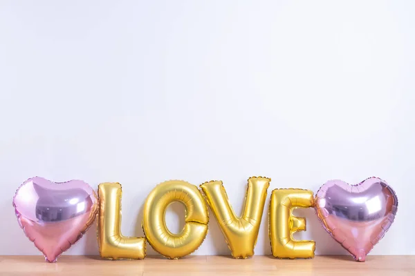 Dia dos Namorados, Conceito de design de dia da mãe - Balão bonito com forma de amor palavra em um piso de madeira leve e fundo de parede branca, close up . — Fotografia de Stock