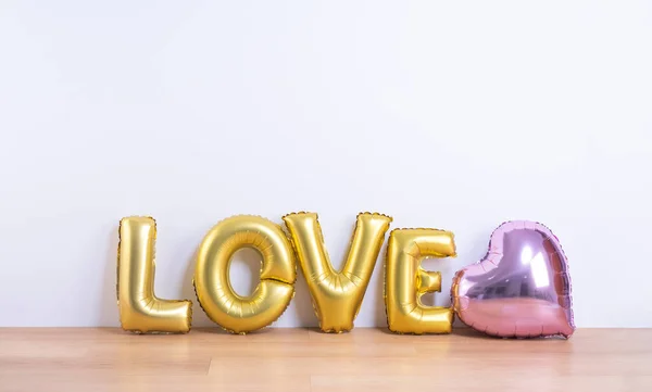 Dia dos Namorados, Conceito de design de dia da mãe - Balão bonito com forma de amor palavra em um piso de madeira leve e fundo de parede branca, close up . — Fotografia de Stock