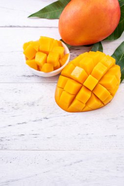 Taze mango, parlak ahşap masa arkasında yeşil yapraklı güzel doğranmış meyve. Tropik meyve tasarımı konsepti, kapat, kopyala.