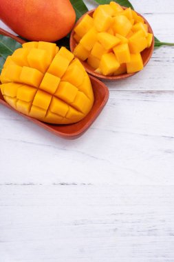 Taze mango, parlak ahşap masa arkasında yeşil yapraklı güzel doğranmış meyve. Tropik meyve tasarımı konsepti, kapat, kopyala.