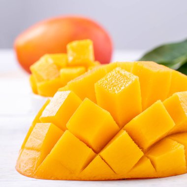 Taze mango, parlak ahşap masa arkasında yeşil yapraklı güzel doğranmış meyve. Tropik meyve tasarımı konsepti, kapat, kopyala.