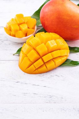 Taze mango, parlak ahşap masa arkasında yeşil yapraklı güzel doğranmış meyve. Tropik meyve tasarımı konsepti, kapat, kopyala.