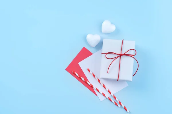 San Valentino, il concetto di design della festa della mamma - Confezione regalo avvolta in bianco, rossa isolata su sfondo azzurro pastello, posa piatta, vista dall'alto . — Foto Stock