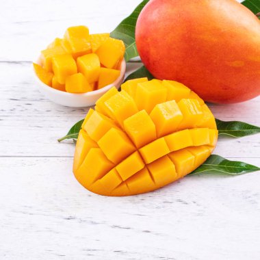 Taze mango, parlak ahşap masa arkasında yeşil yapraklı güzel doğranmış meyve. Tropik meyve tasarımı konsepti, kapat, kopyala.