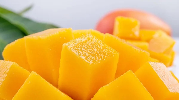 Fresh mango,beautiful chopped fruit with green leaves on bright wooden table background. Tropical fruit design concept, close up, copy space. — 스톡 사진