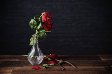 Koyu gri arka planda solmuş gül ve yaprakları dökülen ahşap masa, üzgün sevgililer günü romantizmi tasarım konsepti, kopyalanmış, uzay, kopyalama.