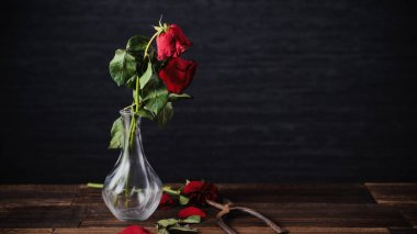 Koyu gri arka planda solmuş gül ve yaprakları dökülen ahşap masa, üzgün sevgililer günü romantizmi tasarım konsepti, kopyalanmış, uzay, kopyalama.