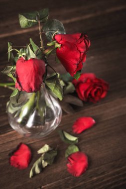 Koyu gri arka planda solmuş gül ve yaprakları dökülen ahşap masa, üzgün sevgililer günü romantizmi tasarım konsepti, kopyalanmış, uzay, kopyalama.