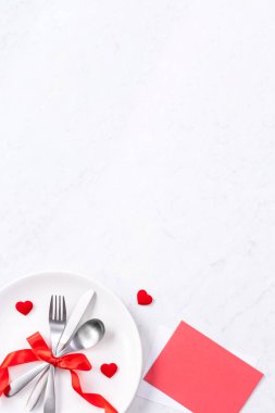 Sevgililer Günü, Anneler Günü, tatil yemeği, ziyafet tasarım konsepti - mermer arka planda beyaz tabak ve kırmızı kurdele, üst manzara, düz yatış.