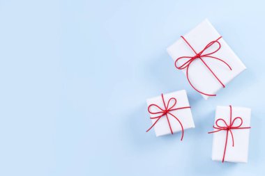 Sevgililer günü, anneler günü sanat tasarım konsepti kırmızı, beyaz paketlenmiş hediye kutusu pastel rengi açık mavi arka plan, düz alan, üst manzara.