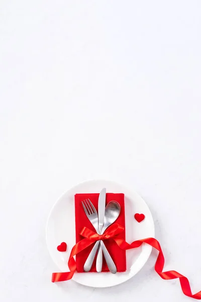 Valentine\'s Day, Mother\'s Day, holiday dating meal, banquet design concept - White plate and red ribbon on marble background, top view, flat lay.