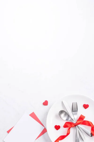 Valentine's Day, Mother's Day, holiday dating meal, banquet design concept - White plate and red ribbon on marble background, top view, flat lay.