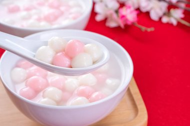 Tang yuan, tangyuan, kırmızı arka planda küçük bir kasede lezzetli kırmızı ve beyaz pirinç köfteleri. Çin Kış Gündönümü Festivali için Asya bayramı yemekleri, kapatıyoruz..