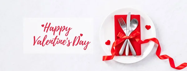 Valentine\'s Day holiday dating meal, banquet greeting card design concept - White plate and red ribbon on marble background, top view, flat lay.