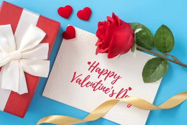 Valentine's Day gift card with greeting word design concept, woman sending gift on vibrant blue background, top view, overhead. — Stock Photo, Image