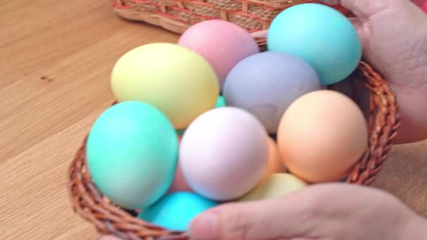 若い女性はイースターの卵狩りの準備をしています 家庭のキッチンで小さな竹のバスケットで装飾された色の卵を設定 閉じる ライフスタイル — ストック動画