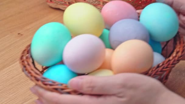 Mladá žena se připravuje na lov velikonočních vajec, nastavení zdobené barevné barevné vejce v malém bambusovém koši v domácí kuchyni, zblízka, životní styl, 4K.
