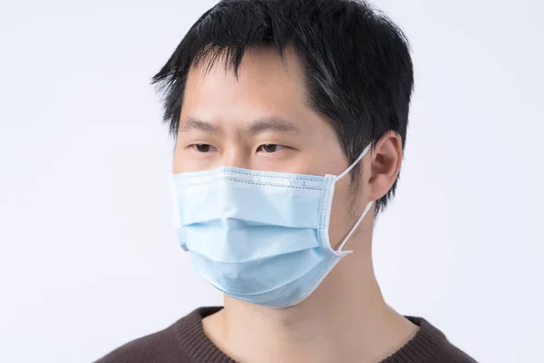 年轻的亚洲男子肖像画 感到恶心 戴着外科用的蓝色面罩来防止感染 空气污染在白色背景下被隔离 去掉了 — 图库照片