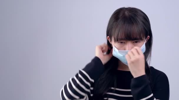 若い女性は咳をしています 体調が悪いです グレーの背景に医療ブルーフェイスマスクを身に着けています 閉じる — ストック動画